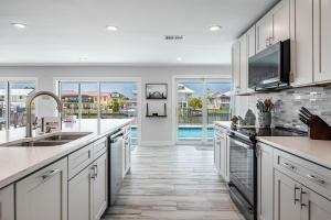 a kitchen with white cabinets and a pool at Good Vibes and Tan Lines! Private Beach with Heated Pool - Villa Good Times, Fort Myers Beach in Fort Myers Beach