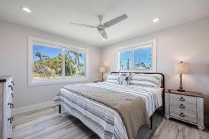 a bedroom with a bed and two windows at Good Vibes and Tan Lines! Private Beach with Heated Pool - Villa Good Times, Fort Myers Beach in Fort Myers Beach