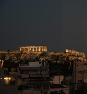 a building on top of a mountain at night at Acropolis View - 500m Metro - At Historical Center in Athens