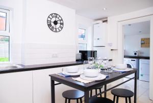 kuchnia ze stołem z krzesłami i zegarem na ścianie w obiekcie Comfortable Stay for 6, Charming 3-Bedrooms near Gloucester Quays with Parking w mieście Hempstead