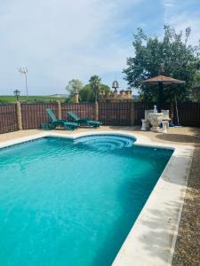 a swimming pool with blue water in a backyard at VFT Las Piedrecitas in Hornachuelos