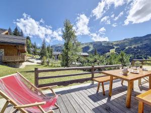 una terrazza in legno con tavolo e sedie. di Chalet typique ski-in/ski-out, cheminée et terrasse, parking, Wi-Fi inclus à Méribel - FR-1-688-15 a Méribel