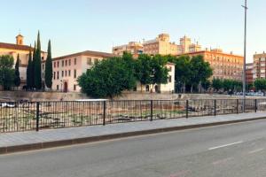 a city street with a fence and buildings at Piso con vistas al Jardín de San Esteban in Murcia