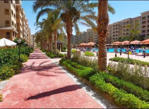 um caminho de resort com palmeiras e uma piscina em Unique studio- Aqua View Resort em El Alamein
