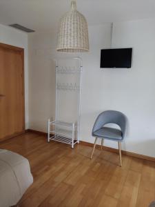 um quarto com uma cadeira, uma televisão e um candeeiro em Apartamentos A Parada do Camiño Padrón em Padrón