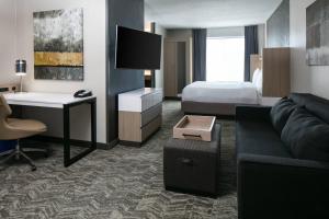 a hotel room with a bed and a couch and a desk at SpringHill Suites by Marriott Tulsa in Tulsa