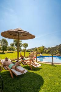 2 persone sdraiate su sedie a sdraio sotto un ombrellone accanto alla piscina di Bruval Eco Retreat a Sandim