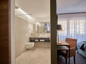 a bathroom with a sink and a toilet and a desk at Panoramahotel Fliesserhof in Fliess