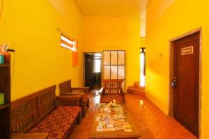 a yellow room with couches and a table at Kampung Osing Inn in Giri