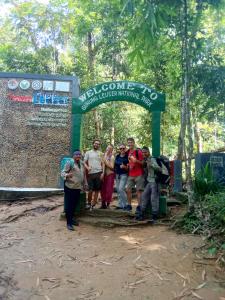 a group of people standing in front of a sign at Jungle treking & Jungle Tour booking with us in Bukit Lawang