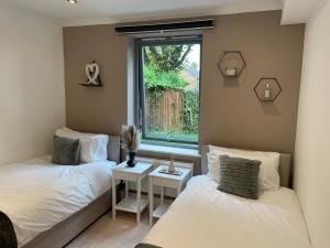 two beds in a room with a window at Perfect Stay for Families & Business in CR2 - with FREE parking & 10mins from East Croydon in Purley