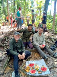 a group of men sitting on the ground with fruit at Jungle treking & Jungle Tour booking with us in Bukit Lawang