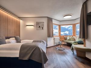Panoramahotel Fliesserhof في فليس: غرفة نوم بسرير واريكة ونوافذ