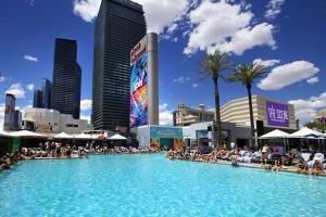 a large swimming pool in a city with people sitting around it at Devine Unit by Planet Hollywood Casino Strip Las Vegas in Las Vegas