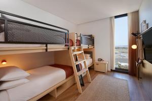 Dormitorio pequeño con literas y escalera en Moxy Sydney Airport en Sídney