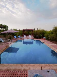 a large swimming pool with chairs and a gazebo at La Novia Marrakech in Tahannout