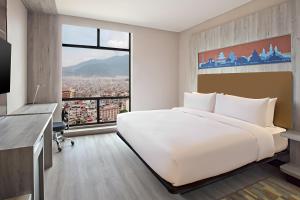 a bedroom with a large white bed and a large window at Aloft Kathmandu Thamel in Kathmandu
