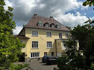 une grande maison jaune avec des voitures garées devant elle dans l'établissement VillaWie, à Rheda-Wiedenbrück