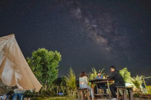 a group of people sitting at a table under the night sky at The Bunker Bir in Bīr