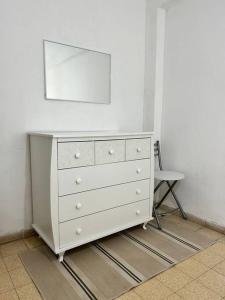 uma cómoda branca com um espelho e uma cadeira em dgania lux em Qiryat H̱ayyim