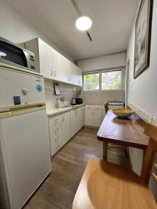 uma cozinha com armários brancos, uma mesa e um frigorífico em dgania lux em Qiryat H̱ayyim