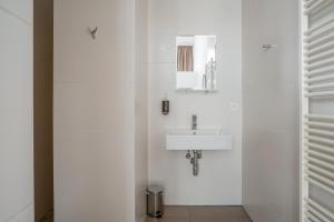 une salle de bain blanche avec un lavabo et un miroir dans l'établissement Smartflats - Central Antwerp, à Anvers 53 autres photos