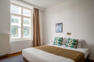 ein Schlafzimmer mit einem Bett und zwei Fenstern in der Unterkunft Smartflats - Central Antwerp in Antwerpen