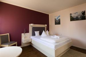 um quarto com uma cama branca e uma cadeira em Landgasthaus Gieseke-Asshorn em Bohmte