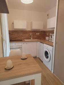 a kitchen with a sink and a washing machine at T2 balnéothérapie, jardin, parking, tram, boulodrome in Blagnac