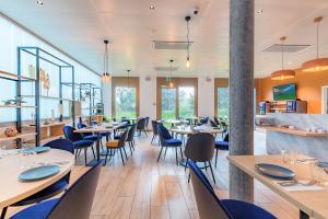 een eetkamer met tafels, stoelen en ramen bij Appart'City Collection Genève Aéroport - Vernier in Genève