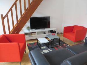uma sala de estar com 2 cadeiras vermelhas e uma televisão de ecrã plano em Au Quai Des Pecheurs em Estrasburgo