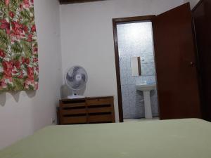 a bedroom with a bed and a bathroom with a fan at Recanto do italiano in Ubatuba