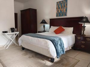a bedroom with a large bed with a blue blanket on it at The Coral in Pretoria