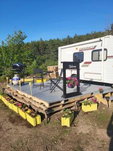 a trailer with a table and some flowers and plants at Moceanset Getaways - Ocean, Mountain & Sunset Views - Cozy Accommodations in Dingwall