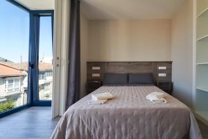 a bedroom with a bed and a large window at Apartamentos Carballal in Palas de Rei