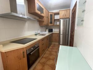 La cuisine est équipée d'armoires en bois et d'un réfrigérateur en acier inoxydable. dans l'établissement Apartamento Alameda del Tajo III Centro Free Parquing, à Ronda