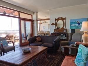 a living room with a couch and a table at Bikini Beach Holiday Home, On the Beach, Sleeps 9! in Gordonʼs Bay
