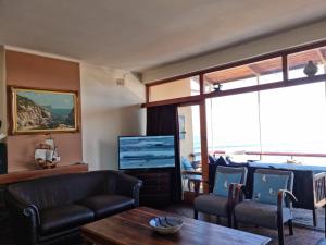 a living room with a couch and a tv at Bikini Beach Holiday Home, On the Beach, Sleeps 9! in Gordonʼs Bay