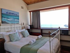 a bedroom with a bed with two pillows and a window at Bikini Beach Holiday Home, On the Beach, Sleeps 9! in Gordonʼs Bay