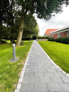 a brick walkway in a yard with a tree at Pidder Lüng in Bargum