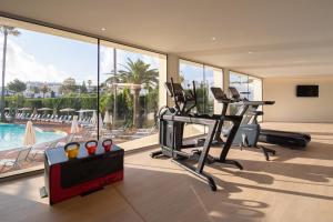 a fitness room with a gym with a swimming pool at JS Portocolom Suites in Portocolom