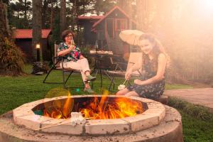 two women sitting around a fire pit in a yard at Pousada Vila 505 in Canela