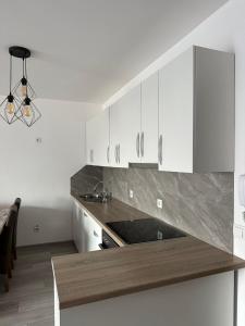 a kitchen with white cabinets and a wooden counter top at Modern Apartment in Ferizaj