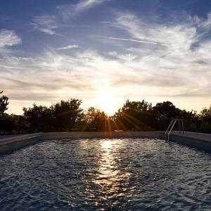 ein Pool mit Sonnenuntergang im Hintergrund in der Unterkunft Autentisereia in Algoso