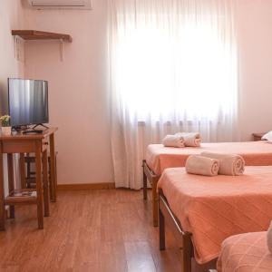 ein Hotelzimmer mit 3 Betten und einem TV in der Unterkunft Autentisereia in Algoso