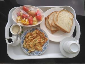 - un plateau avec une assiette de nourriture, du pain et du pain grillé dans l'établissement Lao Tangren Guest House, à Kigali