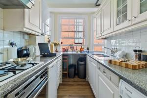 a kitchen with white cabinets and a counter top at Oxford Street London Apartments Hosted by Maysa in London