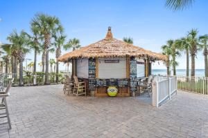 a hut with chairs and a table and palm trees at Calypso Beach Resort & Towers by Panhandle Getaways in Panama City Beach