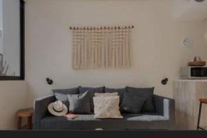 Una sala de estar con un sofá gris con almohadas. en Mayakën-Amazing Urban Jungle -Private Plunge Pool, en Tulum