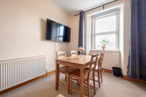 a dining room table with chairs and a television on the wall at 2 Bed Central Ness Apart - May Court in Inverness